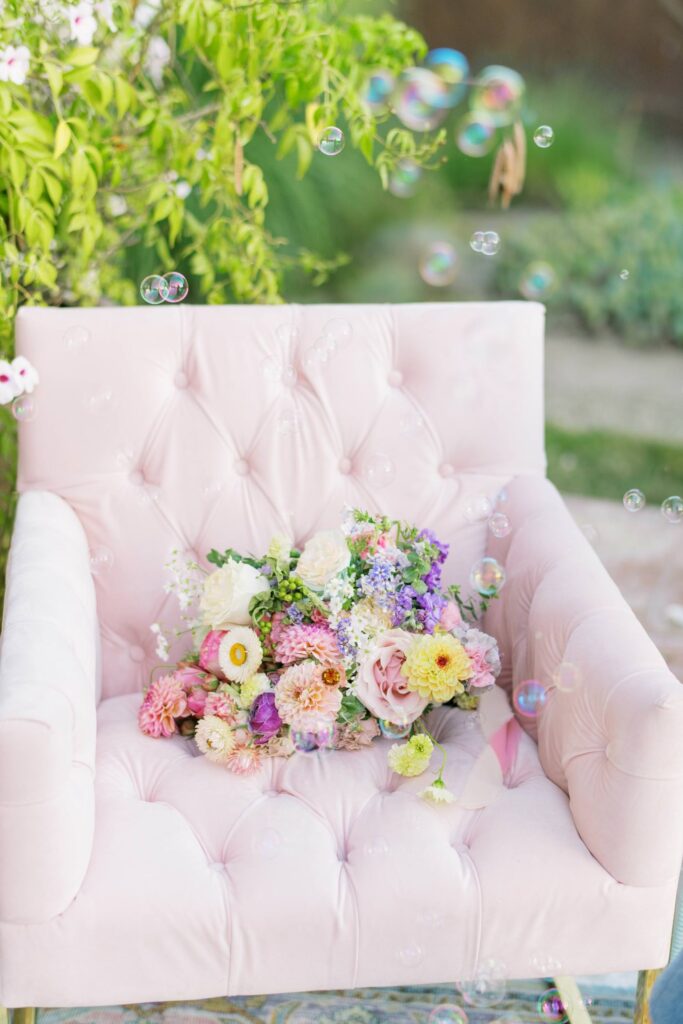 colorful california bridal session light pink velvet chair with bright flower arrangement
