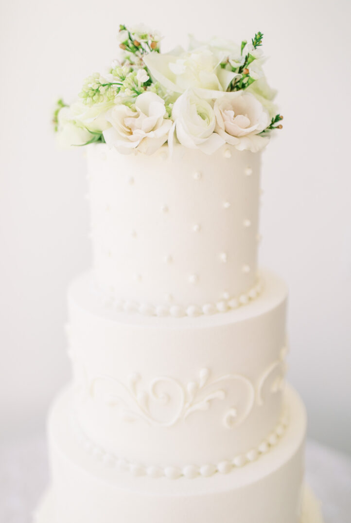 Houston winter wedding cake featuring white roses and ranunculus at the top of the cake
