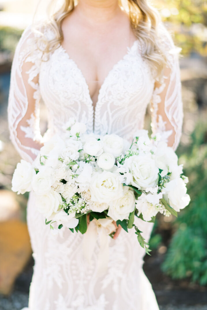 up close detailed shot of wedding dress with a deep plunged neckline and large lace featured on the sleeves