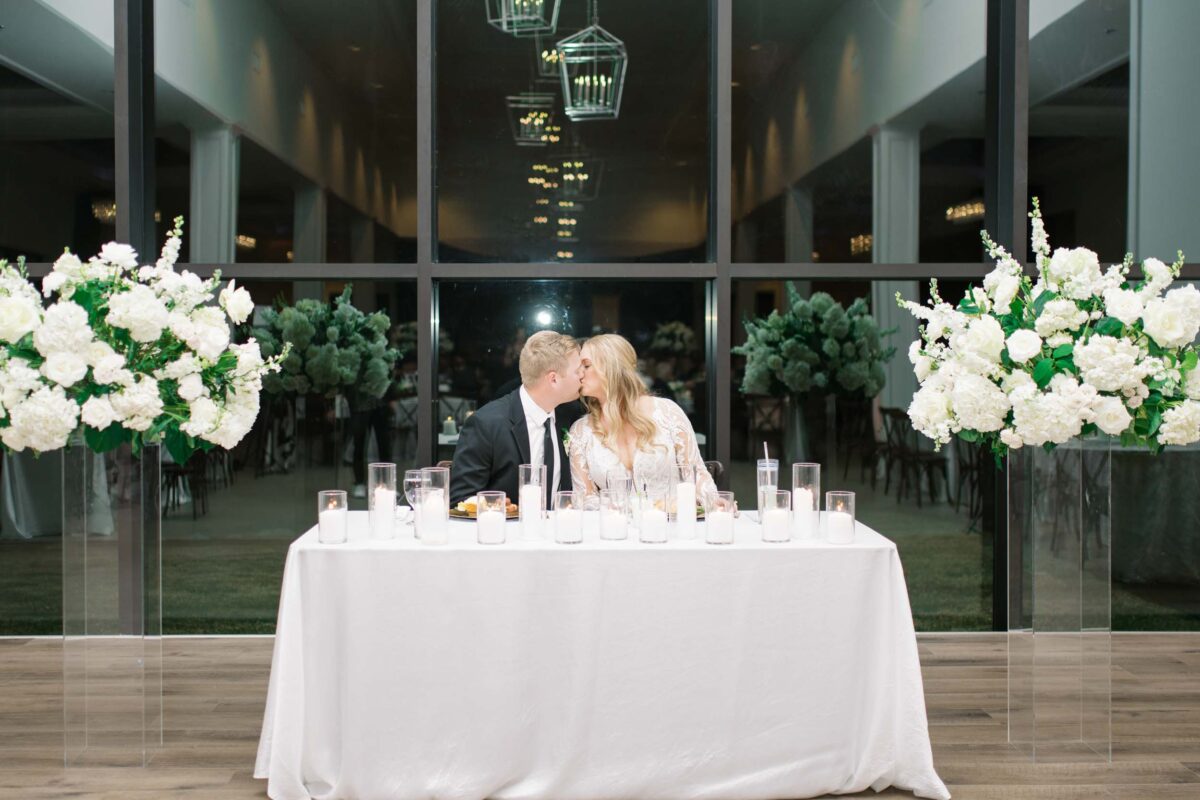bride and groom kissing at the head dinner table during the reception at The Luminaire