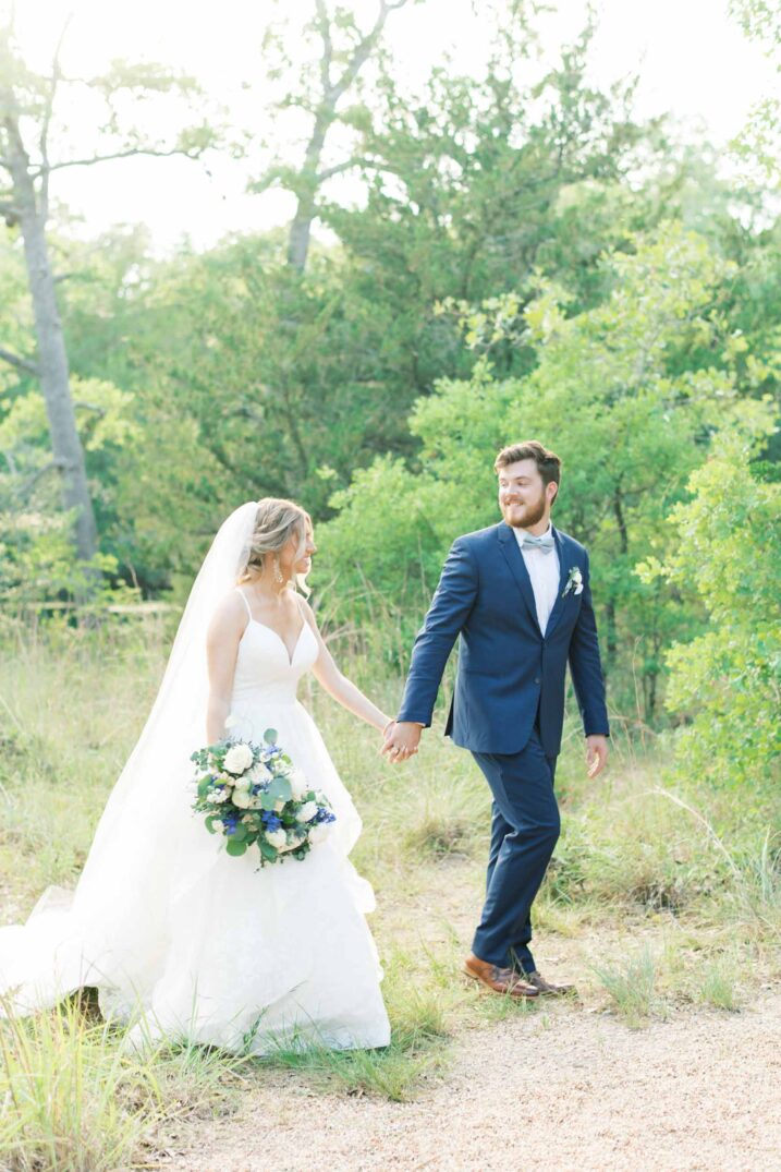 walking bride and groom in the woods holding hands