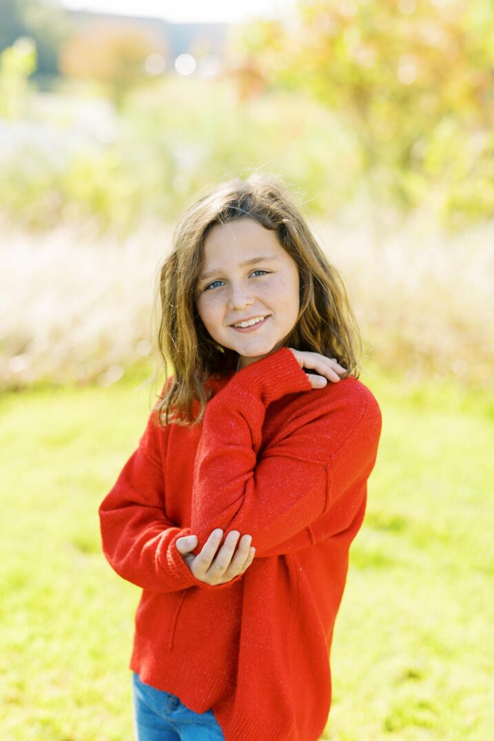 girl wearing festive red sweater and jeans for Christmas card family photos