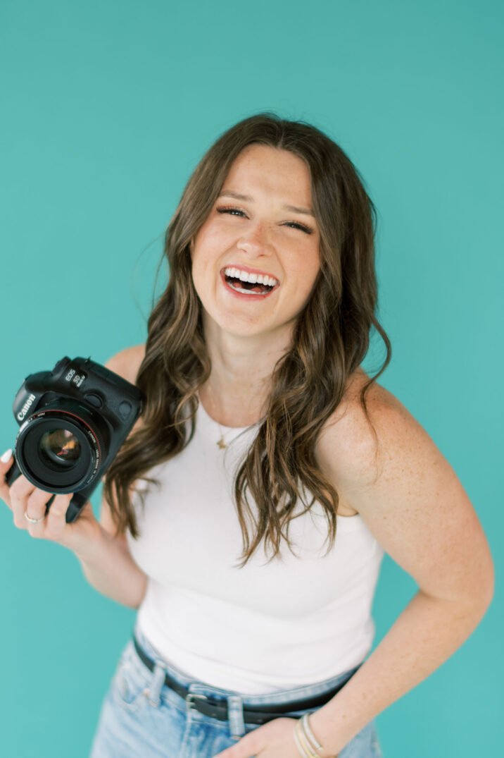 smile laughing photographer closeup of canon 5d mark iv camera behind aqua background