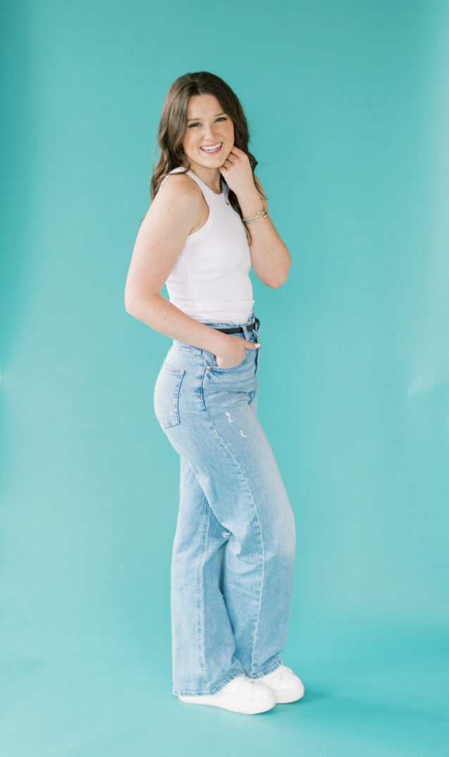 aqua background photo session in light wash jeans and white sneakers