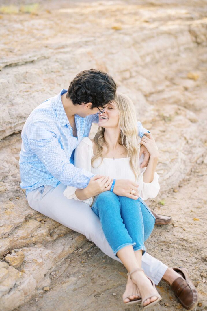 Dallas waterside engagement photos couple sitting on rocky cliff
