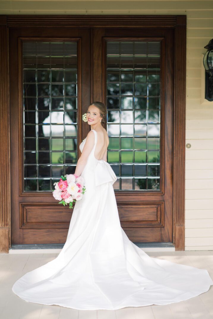 hill country bridal portraits behind grand wooden glass doors and large bow accent on wedding dress