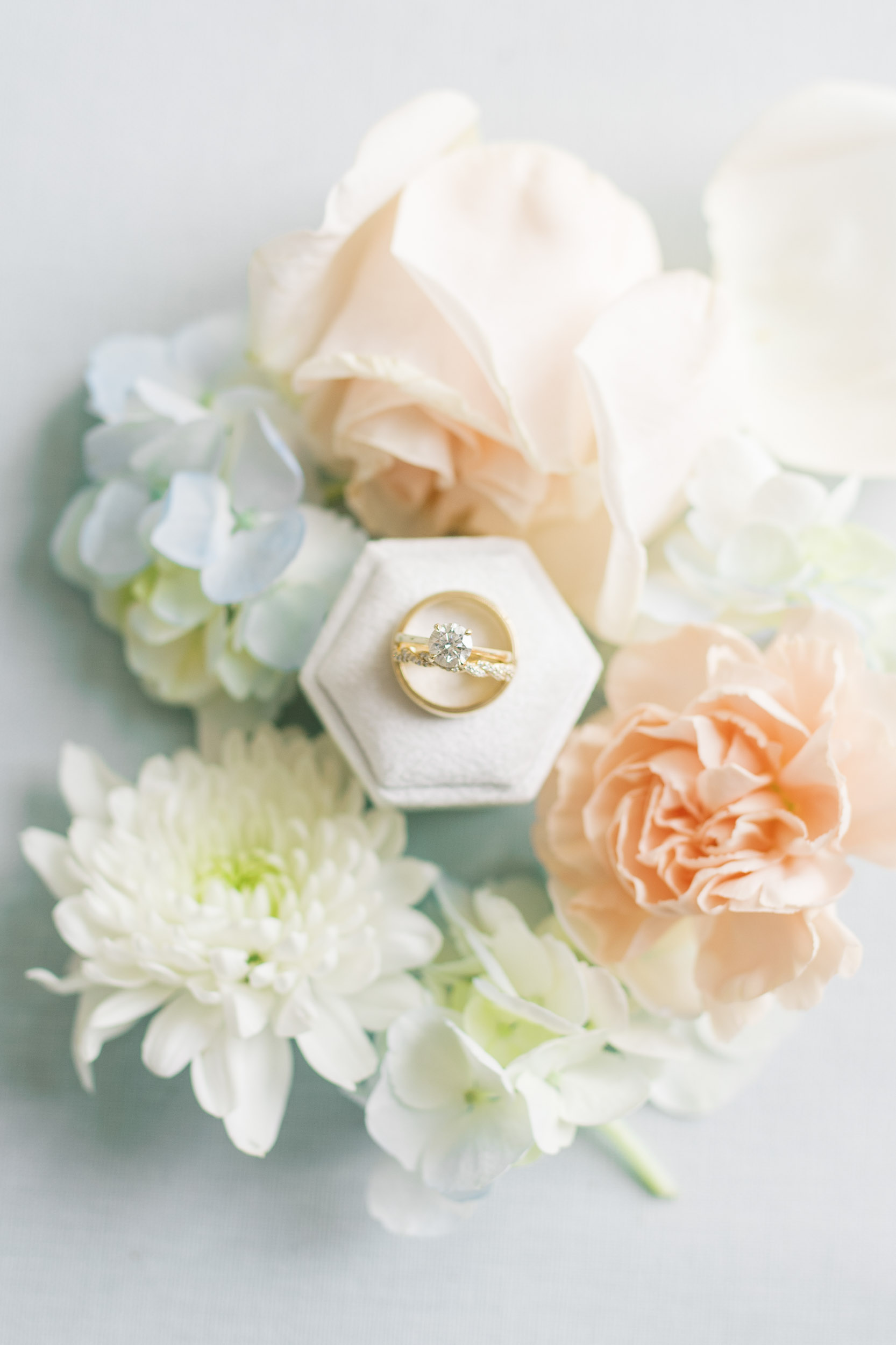 detail shot of wedding ring and bands surrounded by spring flowers