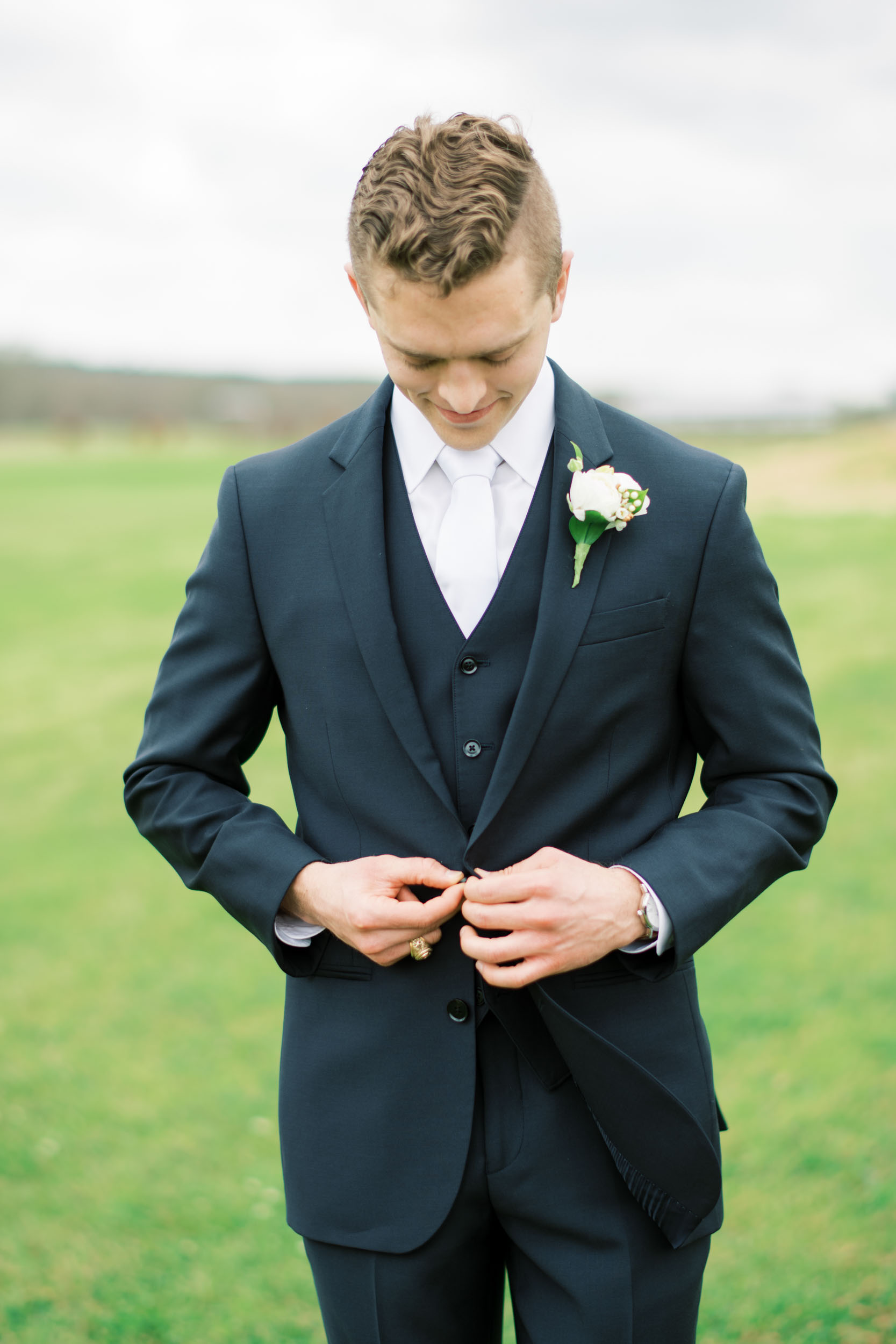 blue farmhouse wedding Houston groom buttoning jacket