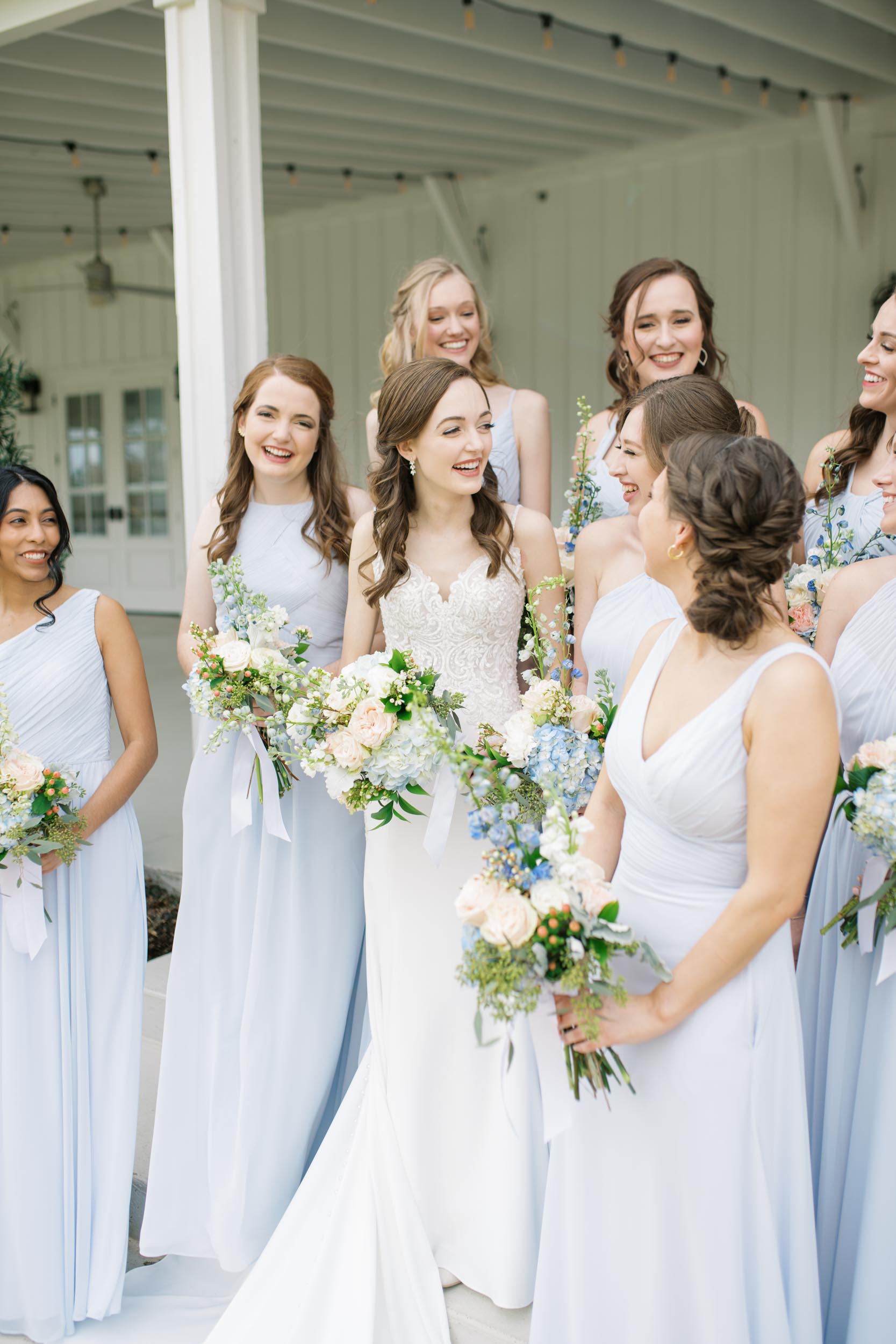 bride laughing alongside bridesmaids staggered wearing light blue dresses