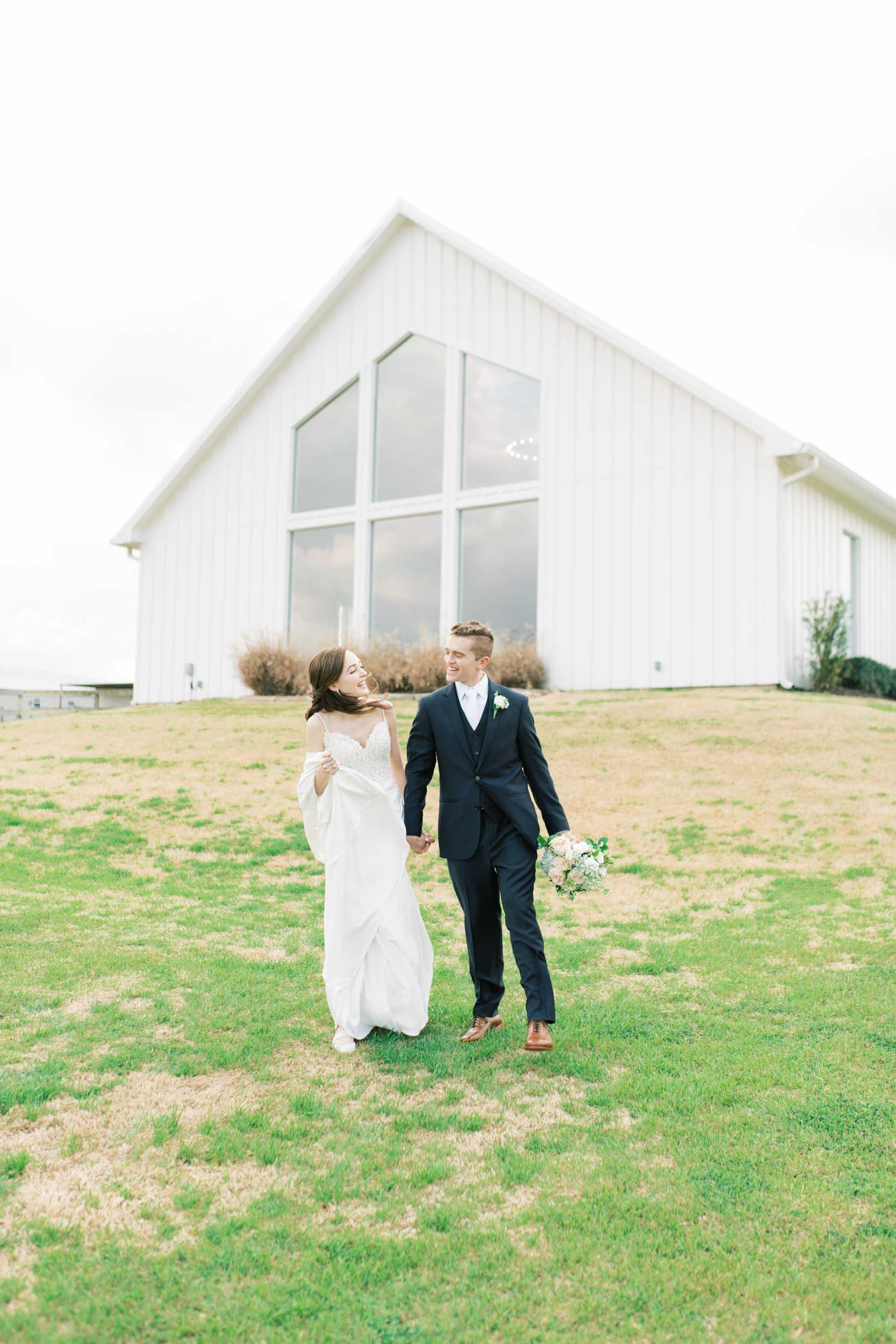 blue farmhouse wedding Houston windy couple walking outside venue