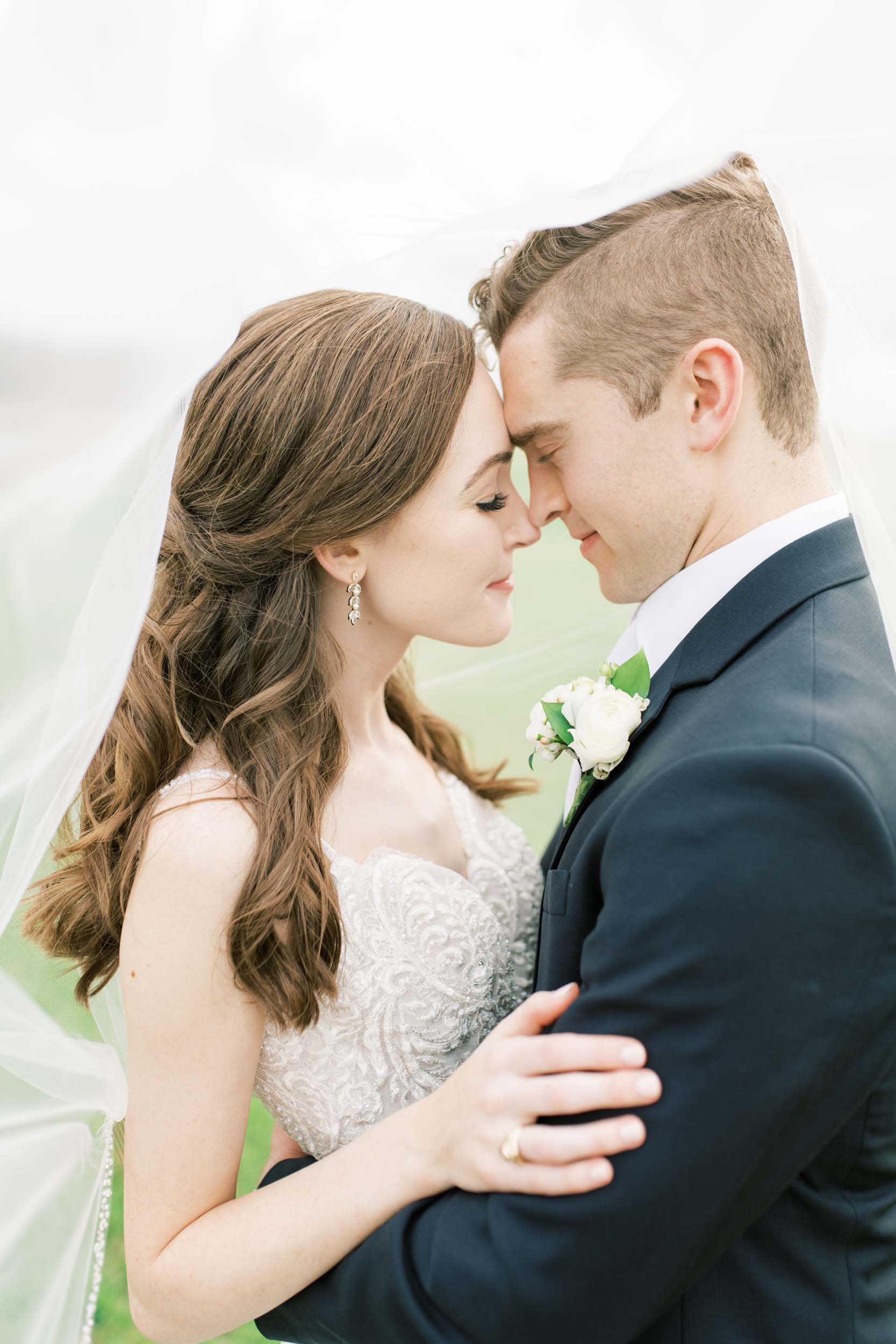 close up of bride and groom with their eyes closed and wedding dress with lace detail