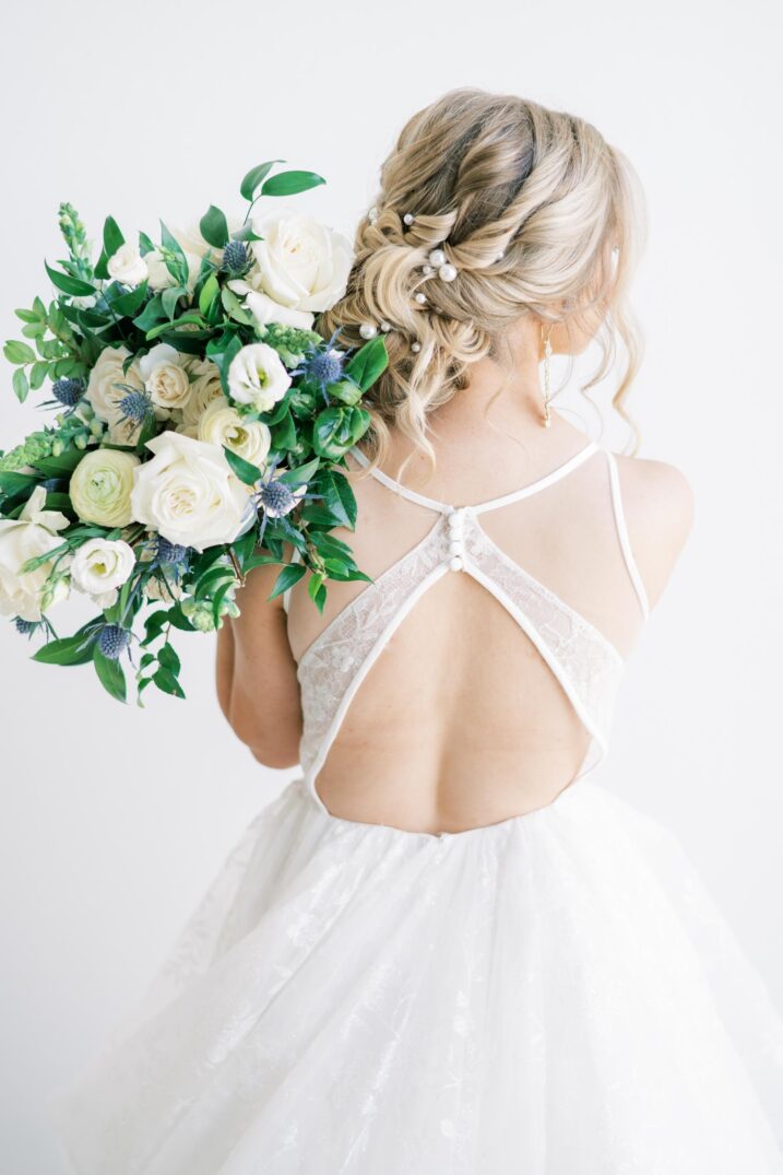 modern studio bridal session intricate back wedding dress and blue thistle white rose bouquet