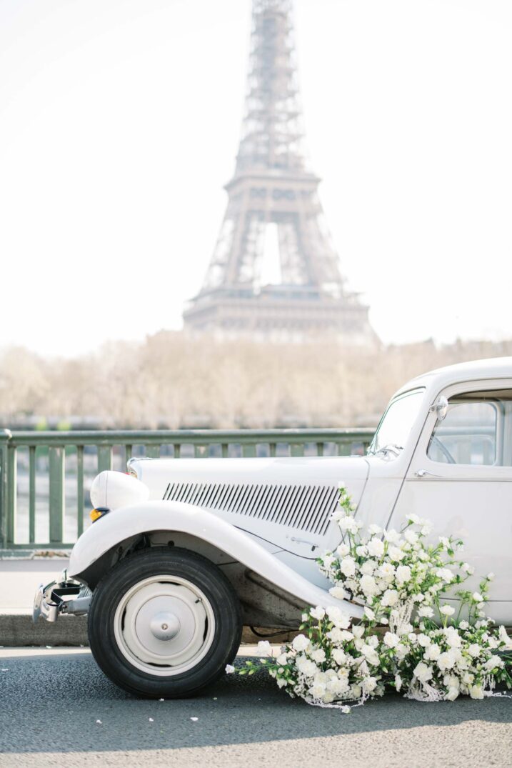 old vintage car with white flowers in front of the Eiffel Tower in Paris, France