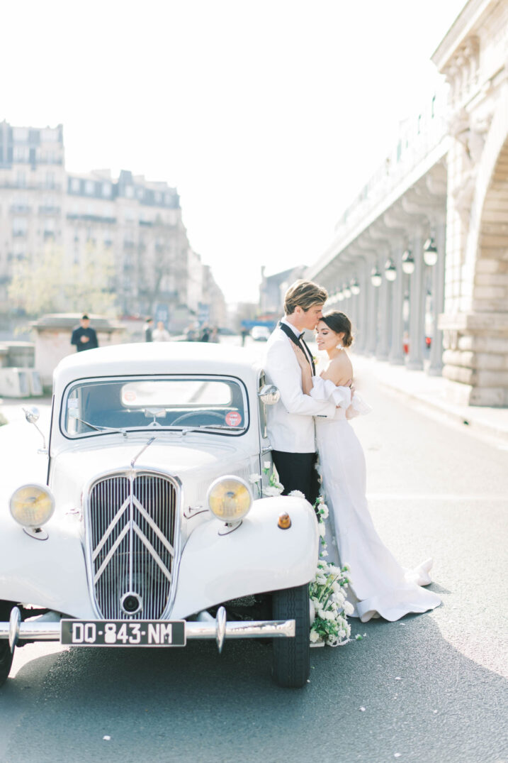 Parisian bride groom Eiffel standing against a white vintage car in the street