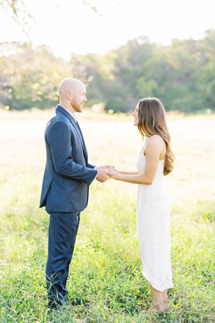 couple exchanging sweet words with one another in a grassy field during their engagement pictures