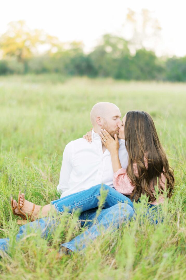 Texas nature engaged couple sitting in grass kissing