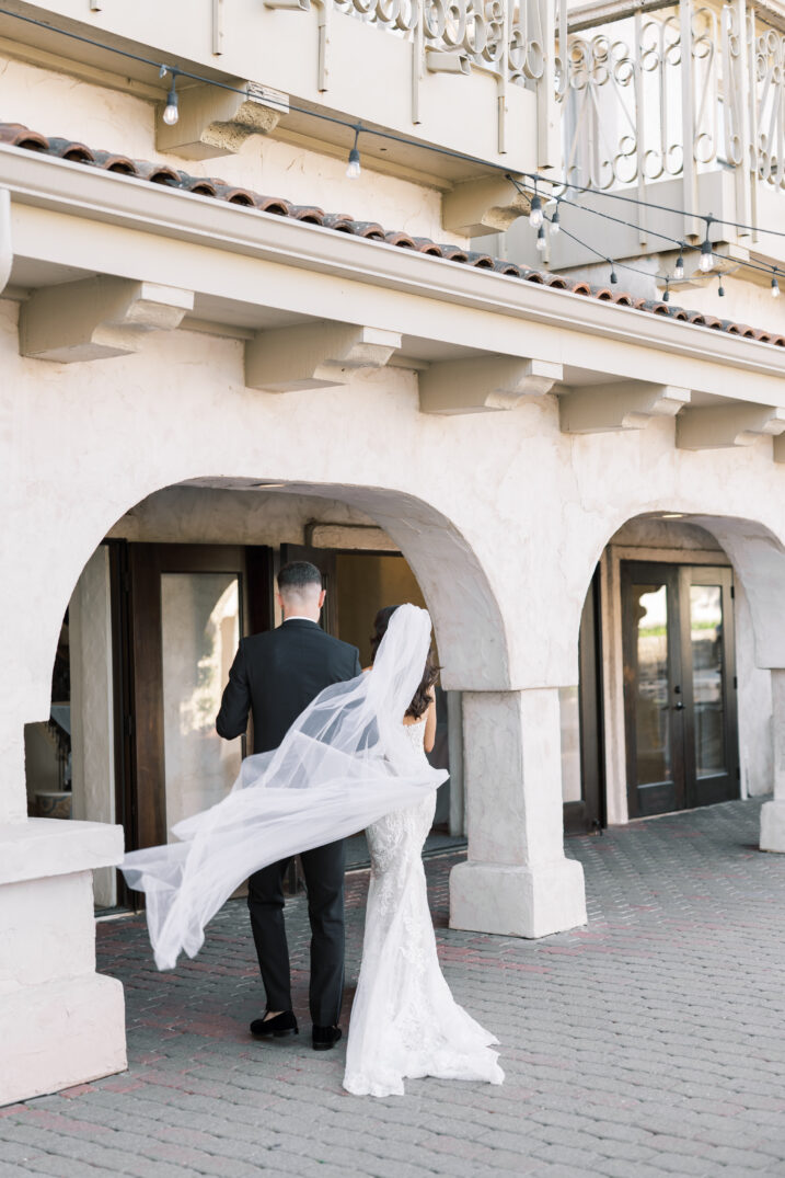 bride and groom walk veil in wind Italian inspired wedding husband and wife travel