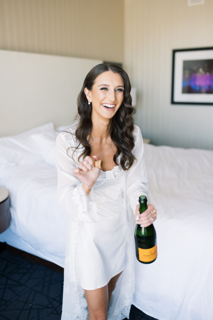 bride champagne pop getting ready for wedding at hotel confident