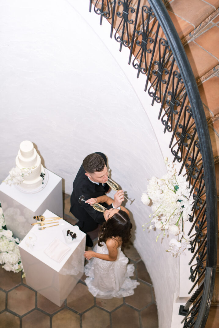 bride and groom champagne exchange from above white floral cake Italian inspired spiral staircase