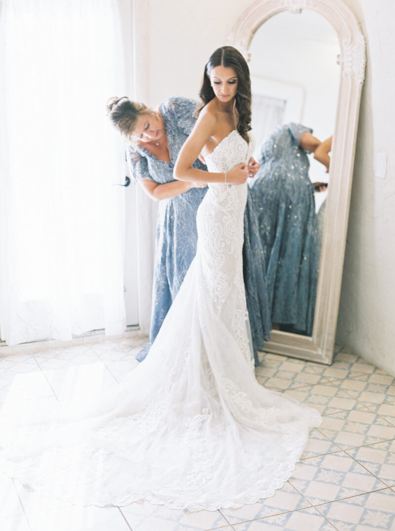 mother of the bride helping with wedding dress mom and daughter getting ready fashion-inspired